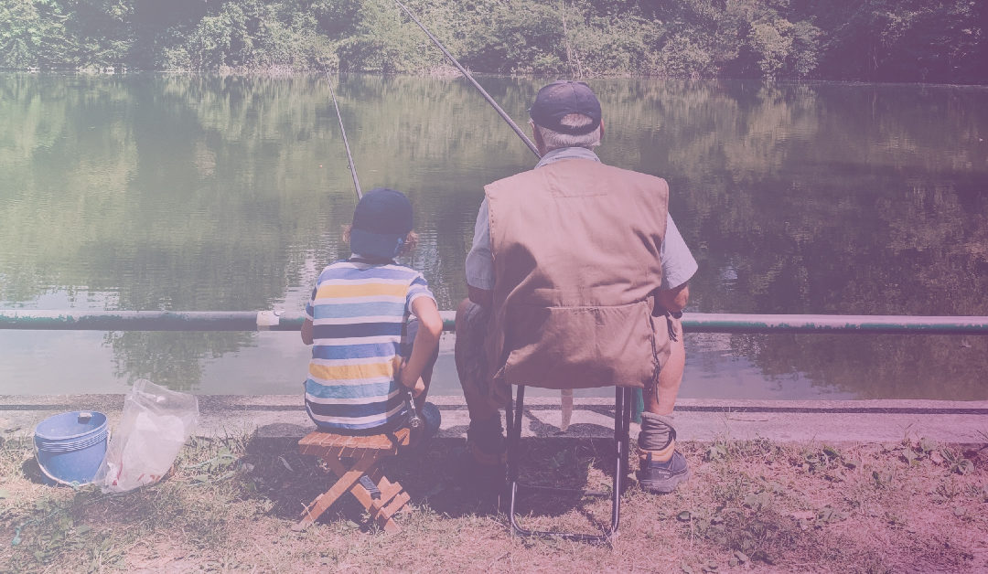 Grandfather and grandson sitting in folding chairs and fishing