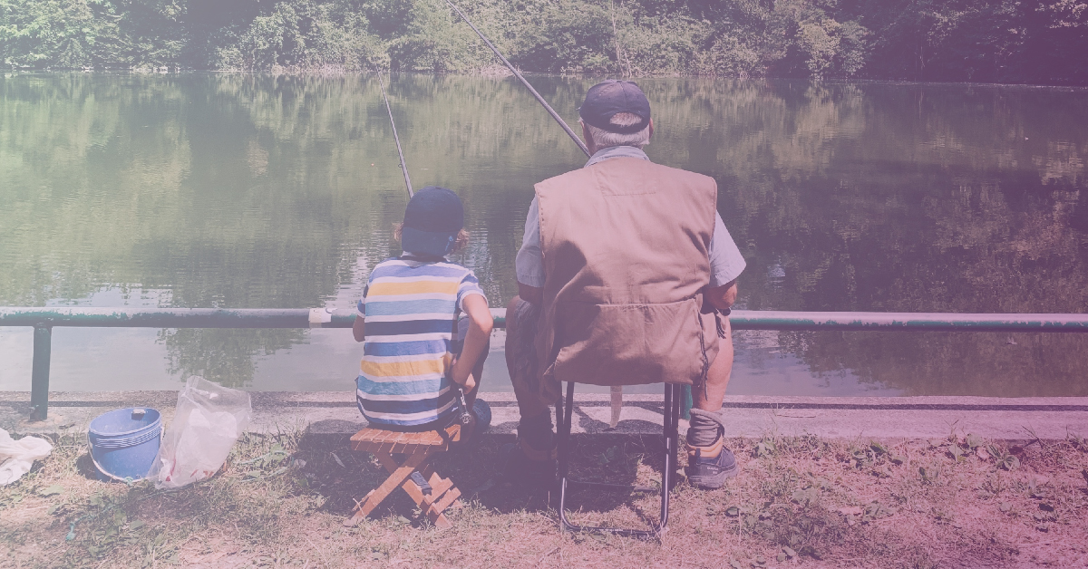 Grandfather and grandson sitting in folding chairs and fishing